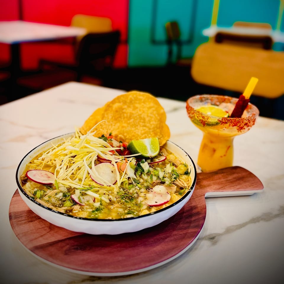Pozole verde with shredded cabbage, radishes, lime, and a side of a mango margarita.